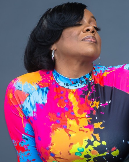 Marsha looking upward in a vivid paint-splatter top.