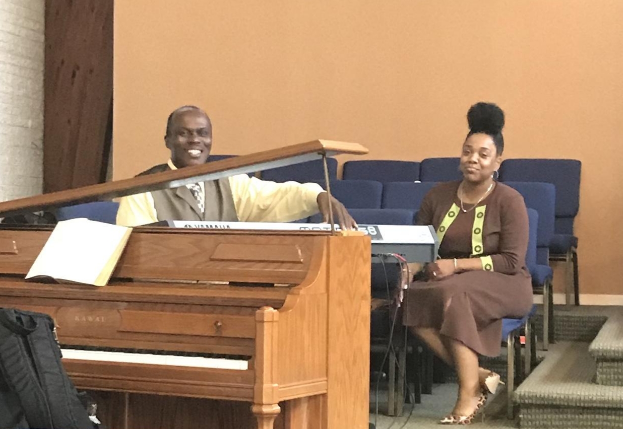 Marsha seated during a worship service beside the piano and keyboard.