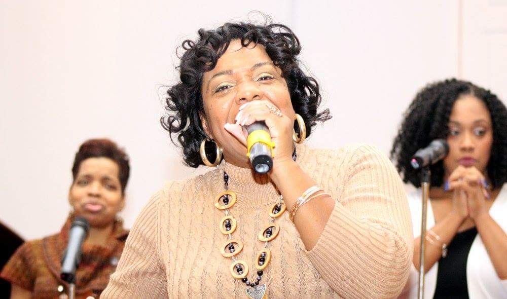 Marsha leading worship with a microphone at a women's gathering.