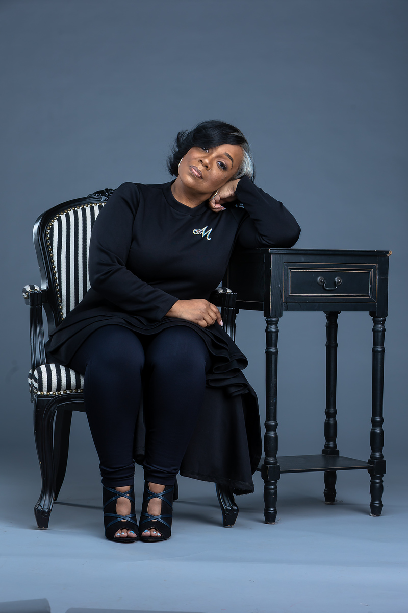 Marsha seated in a black striped armchair in the studio.